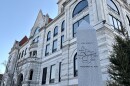 The white brick, gothic architecture Cole County courthouse exterior is in the background. A pillar with a map of Cole County is in the foreground. 