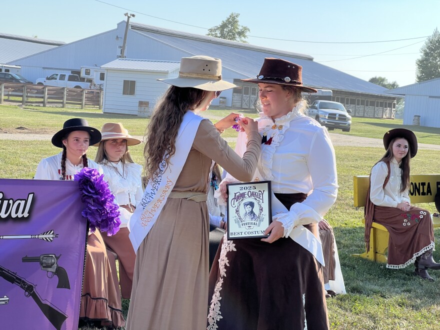 Lauren Wright, last year's Miss Annie Oakley, gives her younger sister Rachael Wright the best costume award at the Annie Oakley Festival in Darke County.