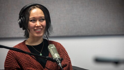 Podcast guest Zoe Hana Mikuta sits in front of a microphone and smiles.