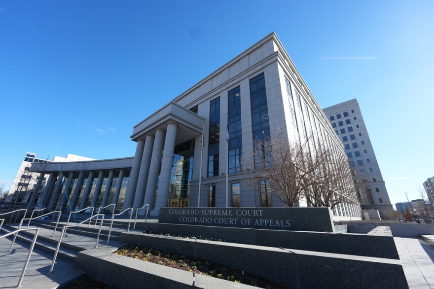 The exterior of the Ralph Carr Judicial Building with tall columns on a blue sky day.