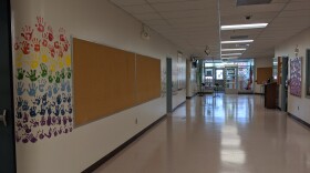An empty hallway with a long corkboard on the wall that's empty as well