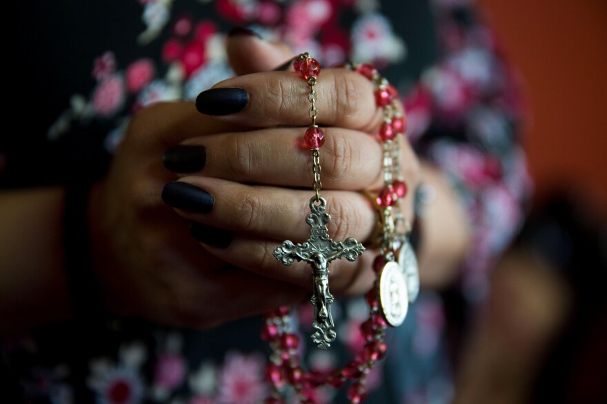 Shawn's wife holds a string of rosary beads that she uses when she prays.