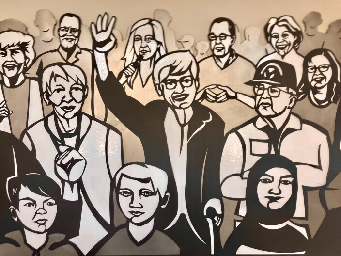 A close-up of a mural inside the new Wassmuth Center for Human Rights. It shows a variety of diverse people standing in together in a group, in a stylized black and white illustration. 