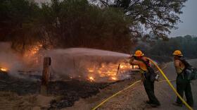 Firefighters from Sequoia Engine 45 cool off the edge of the burnout completed by the Springville Hotshots down a dozer line to Road 81 just north of the Mammoth Pools Trailer Park on the evening of September 10, 2020 as containment efforts continue on the Creek Fire.