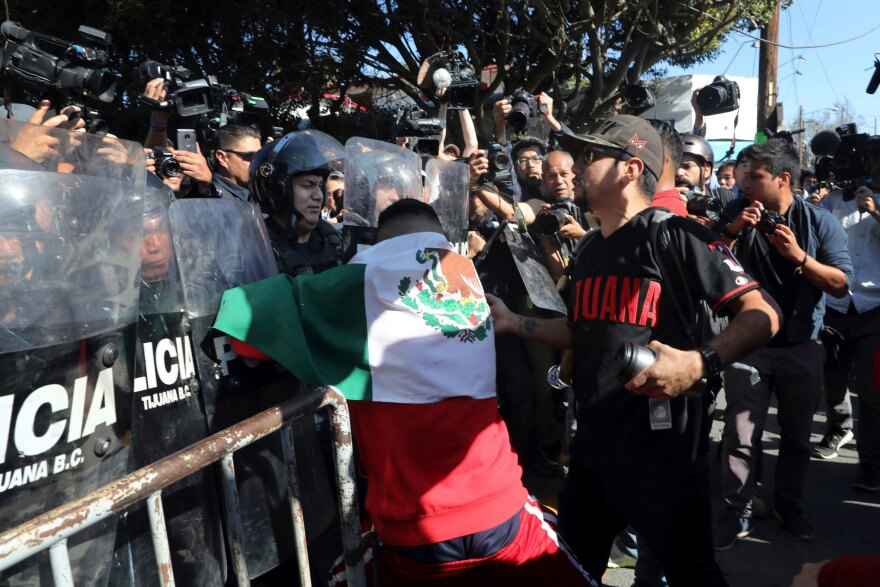 Police stand guard to protect a migrant shelter as demonstrators protest the presence of thousands of Central American migrants in Tijuana, Mexico, on Sunday.