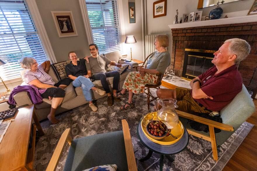 Pam McColl, Jacqui Comstock, her husband Holger Buchholz, Jacqui’s mother Ruth and Pam’s husband Steve have a conversation in the McColl’s living room in Roslindale.