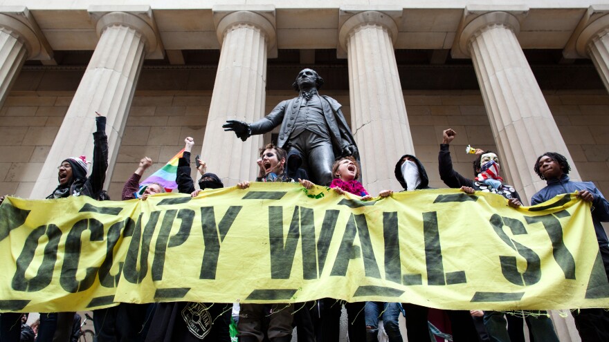 Occupy Wall Street demonstrators stand and cheer in front of the George Washington statue on Wall Street. Millennials were heavily involved in this movement.