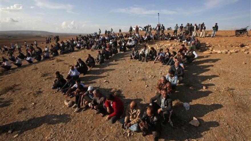 Kurds sit in formation to form the initials of the People's Protection Unit, or YPG, the main Kurdish militia in Syria, on a hilltop overlooking Kobani just over the border, in support of Syrian Kurds fighting ISIS, on Wednesday. Turkey believes the People's Protection Unit have ties to a Kurdish group in Turkey that is the Turkish government considers a terrorist organization.