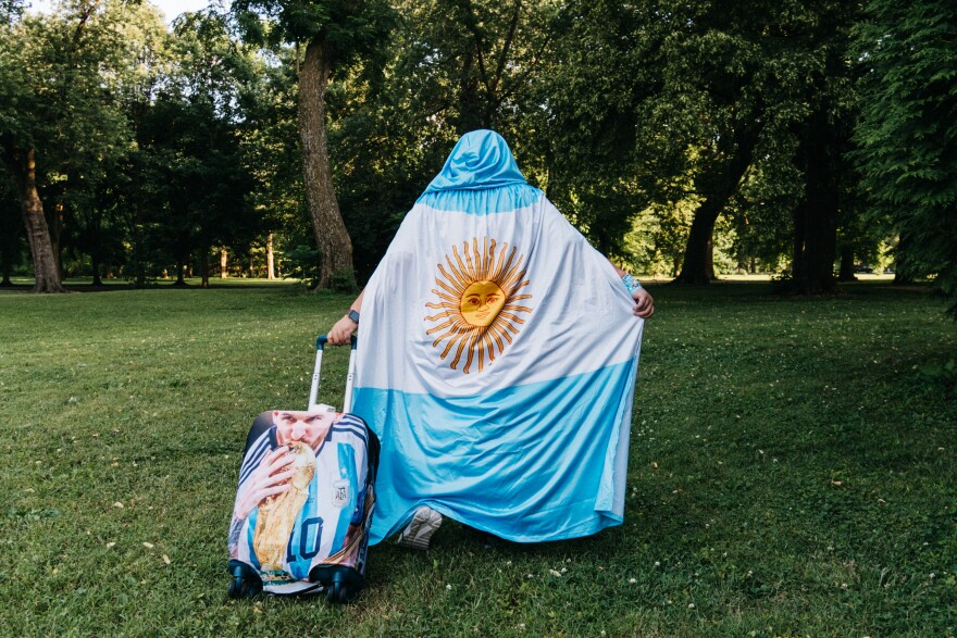 Tina Lanius, of St. Louis' Shaw neighborhood, shows off her Leonel Messi-wrapped suitcase and Argentina flag cape at Tower Grove Park on Tuesday.