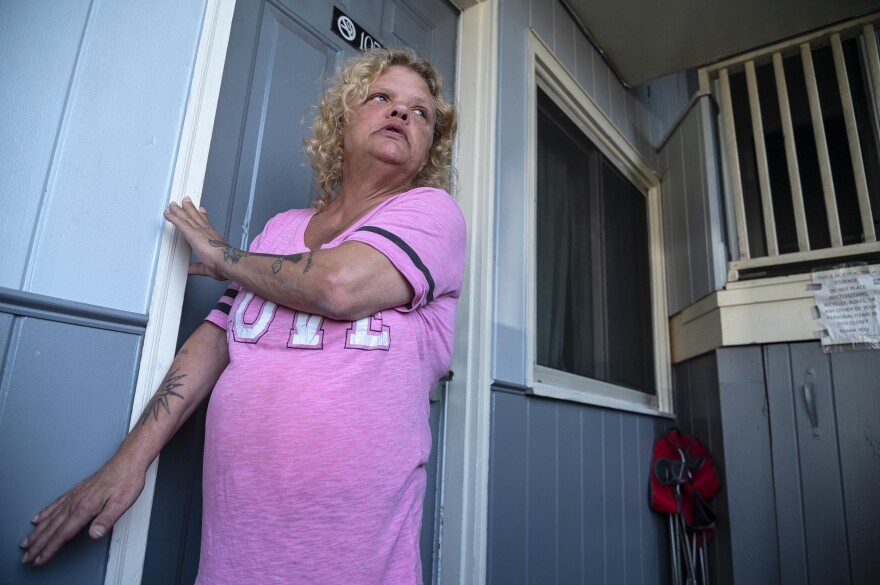 A woman stands next to the door of a motel room