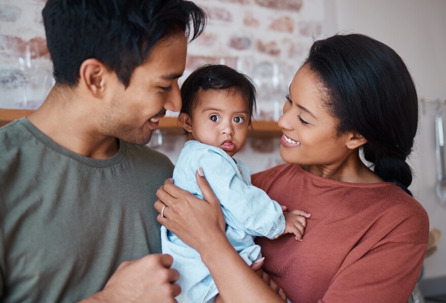 Two parents holding a baby between them