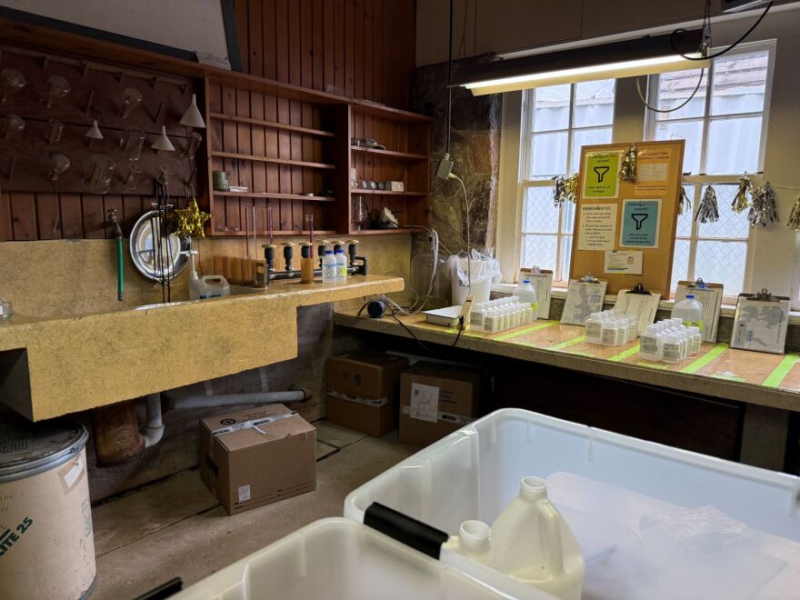 Picture of an old laboratory. There are funnels, plastic bottles and a sink in the background.