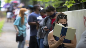 A woman reads as she waits in line to vote, Tuesday, June 9, 2020, in Atlanta. She told AP she had been in line for almost two hours.