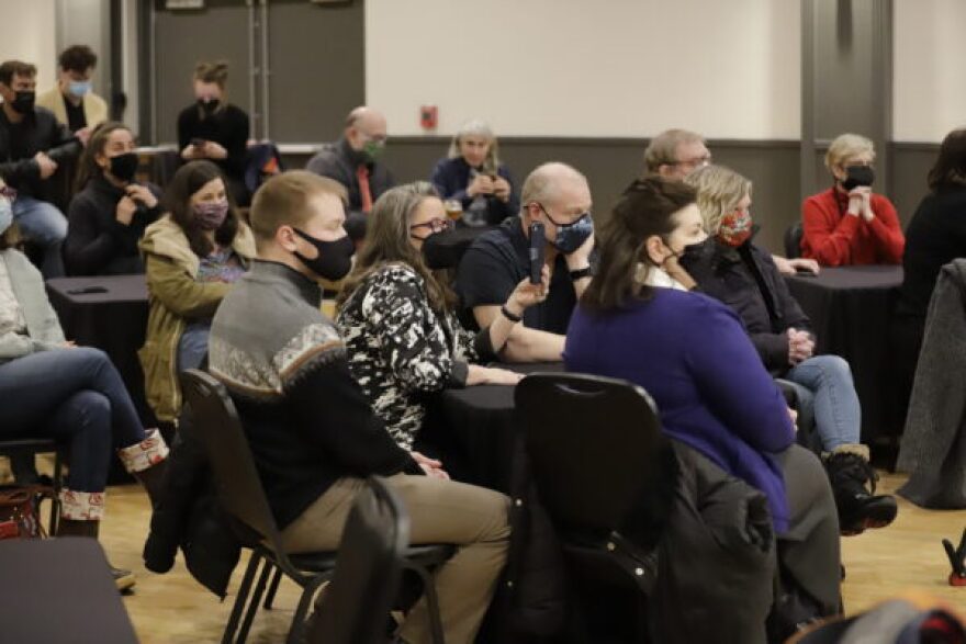 People wearing masks sit in chairs