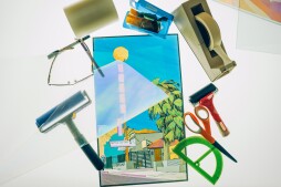 A polage image of a historical motel sits on a table surrounded by art materials.