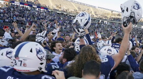 Fans stormed the field and celebrate with players after Connecticut defeated Liberty in an NCAA college football game in East Hartford, Conn., Saturday, Nov. 12, 2022.