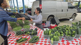 Food Justice Director of Tikkun Ha Ir Amanda McVann hands an empty carton to fill with vegetables to farmer Jenny Yang at the Fondy Farmers' Market.
