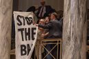 A Missouri Senate doorman shuts down protestors with a "stop the ban" banner in the Senate's upper gallery Wednesday evening