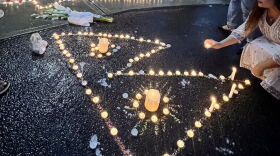 A candle arranged in the shape of the Nepali flag at a vigil for Rasuwa flood victims outside an Albany temple. 