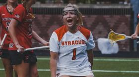 Syracuse attacker Olivia Adamson yells in the center of the photo as her stick drops to the ground