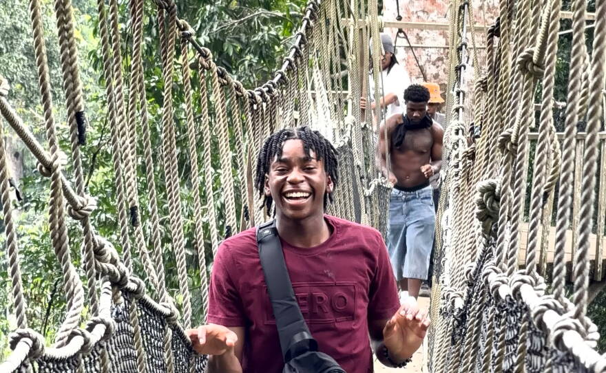 A young man crosses a narrow bridge in Ghana.