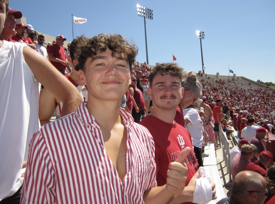 Two students pose for picture at IU football game. 