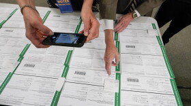 A canvas observer photographs Lehigh County provisional ballots as vote counting in the general election continues, Nov. 6, 2020, in Allentown, Pa. A review by The Associated Press in the six battleground states disputed by former President Trump has found fewer than 475 cases of potential voter fraud, a minuscule number that would have made no difference in the 2020 presidential election. Democrat Joe Biden won Arizona, Georgia, Michigan, Nevada, Pennsylvania and Wisconsin and their 79 Electoral College votes by a combined 311,257 votes out of 25.5 million ballots cast for president.