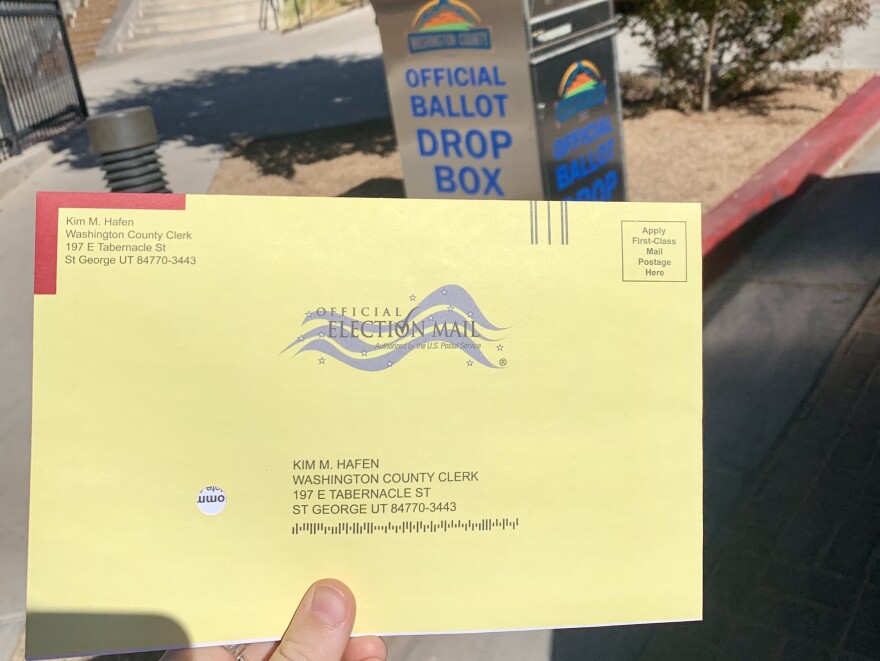 A photo of a ballot in front of a ballot drop off box. 