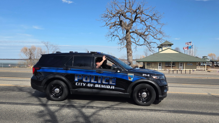 Officer Chad Museus waves at the community members gathered on Bemidji Avenue for his final escort on April 16, 2026.