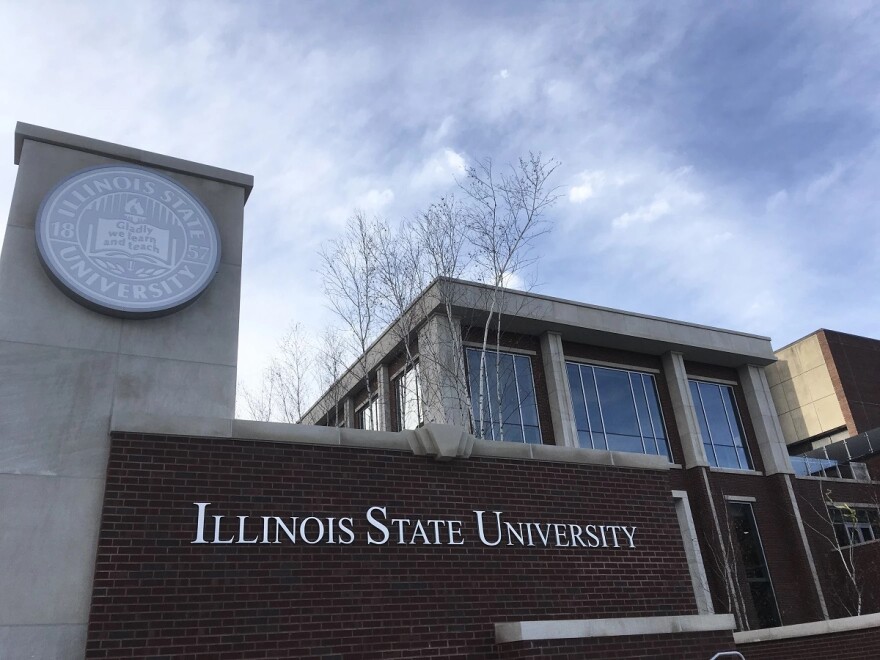 The exterior of Illinois State University's Bone Student Center. A pillar with the school's insignia on the left, a brick sign that has silver letters spelling the university's name. Behind the brick is part of the building.