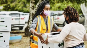 Volunteers wear face masks as they give away boxes of food at a community center. (Getty Images)