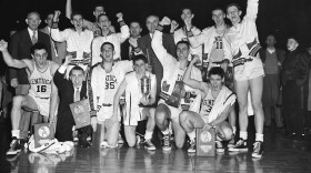 FILE - The Kentucky basketball team, which won the 1951 NCAA basketball championship, celebrates in Minneapolis, March 28, 1951, as it displays the team trophy and individual plaques. At center right is coach Adolph Rupp. Team members are, front row from left: Louis Tsioropoulos, C.M. Newton, Bobby Watson, Cliff Hagen, Lucian Whitaker and Frank Ramsey. Rear, from left: Dwight Price, Bill Spivey, Guy Strong, Roger Layne and Shelby Linville. (AP Photo/Chet Magnuson, File)