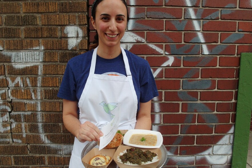 Mana Heshmati, founder of the Detroit-based Peace Meal Kitchen, stands outside of the Detroit City Distillery in Eastern Market during a fundraising event for the ACLU of Michigan. Within two hours, she sold out of her a la carte menu, which included <em>ghormeh sabzi, </em>a Persian beef stew, a vegetarian cream of barley soup, and <em>shirini keshmeshi</em>, delicate rosewater raisin cookies.