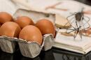 Eggs and a whisk on an open cookbook