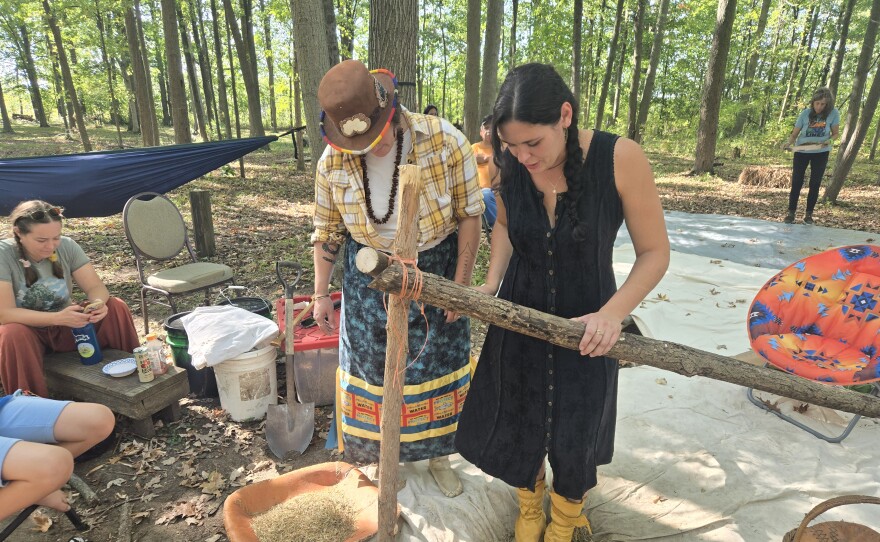 Cortney Collia instructs a rice camp attendee on how to dance in a jigging pit to help get the rice grain out of its shell.