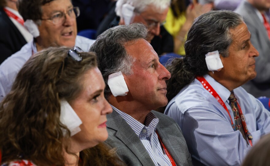 People wear bandages — and bandage-like squares — on their ears at the Republican National Convention at the Fiserv Forum in Milwaukee. Delegates have adopted the white patches in a show of solidarity with former President Donald Trump, who was injured in a shooting at a campaign rally last weekend.