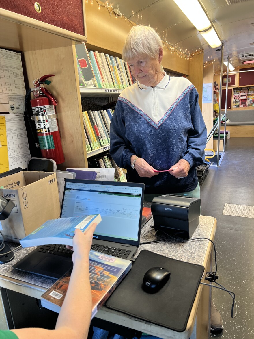 Priscilla Trowbridge checks a book out from the Flagstaff City-Coconino County library Bookmobile.