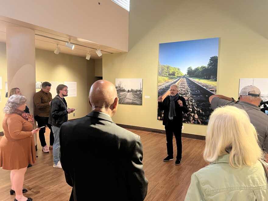 Alan Govenar stands in the center of a crowd at the African American Museum of Dallas with his photos behind him