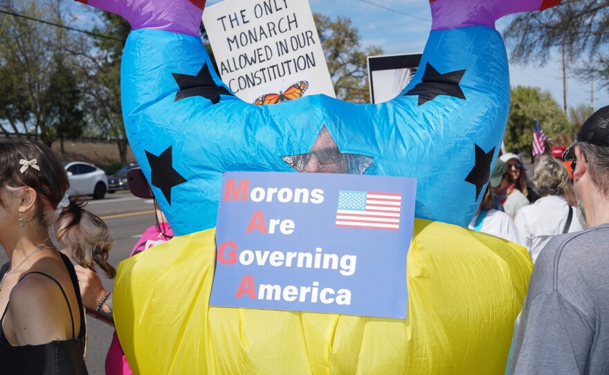 Person in a colorful inflatable outfit holding a sign
