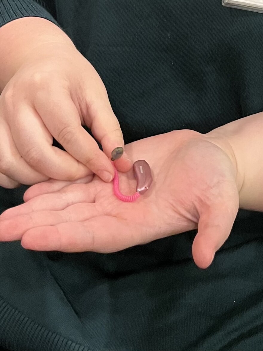 A hearing aid sits in the palm of a person's hand.