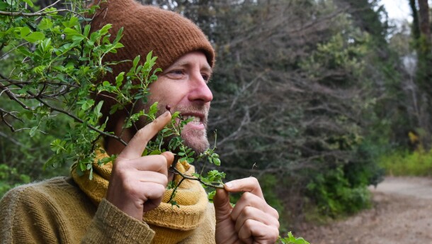 Environmental activist Robin Greenfield points to a rose hip along a walking path at Davidson College.