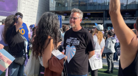 Valkyries fan and trans advocate Arne Johnson speaks to the press while wearing a t-shirt that reads "Thank you Gabby Williams and Coach Nakase."