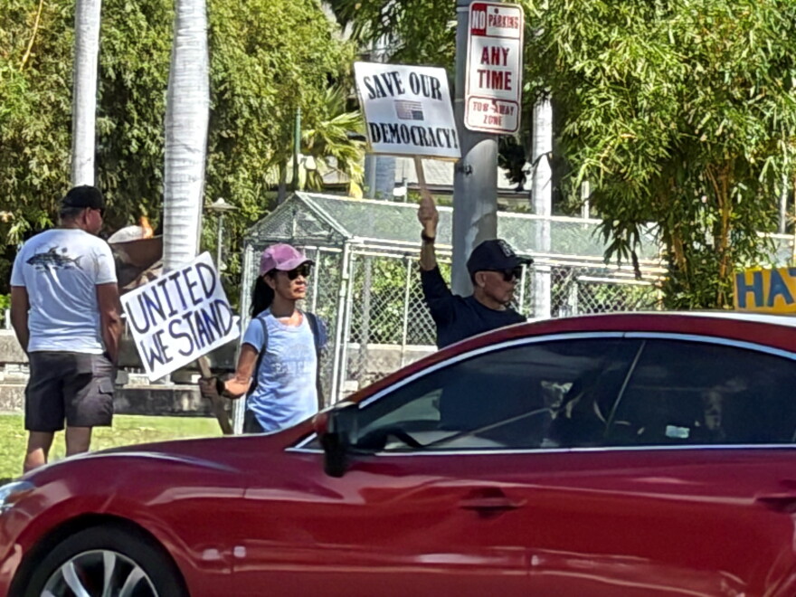 Protestors hold signs along the street during the No Dictators rally on Oct. 17, 2026.