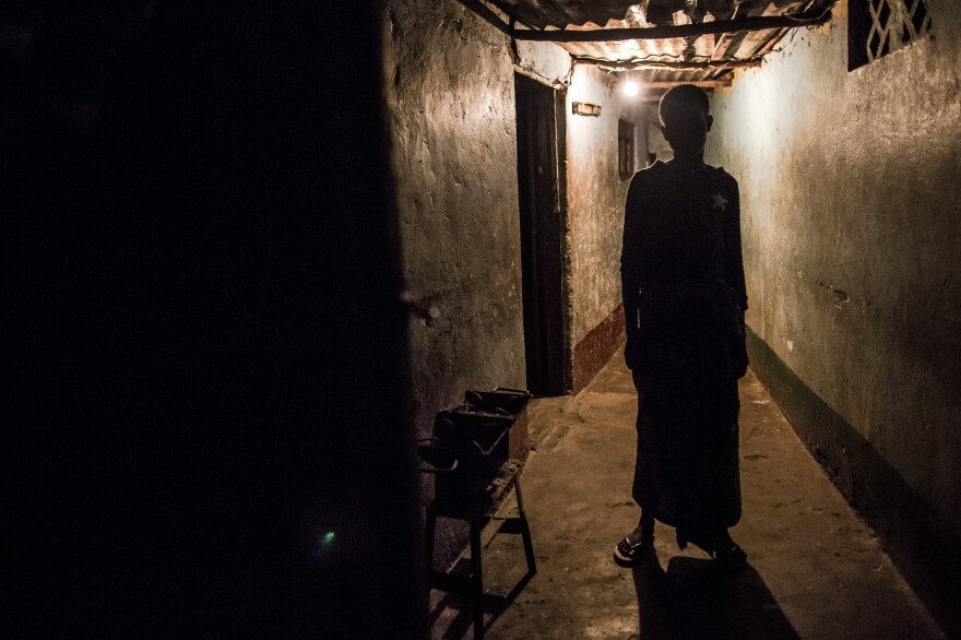 A sex worker waits outside a room she rents in Beira, Mozambique. Her client, inside, will pay 50 meticais for 5 minutes with her — that's about 75 cents.