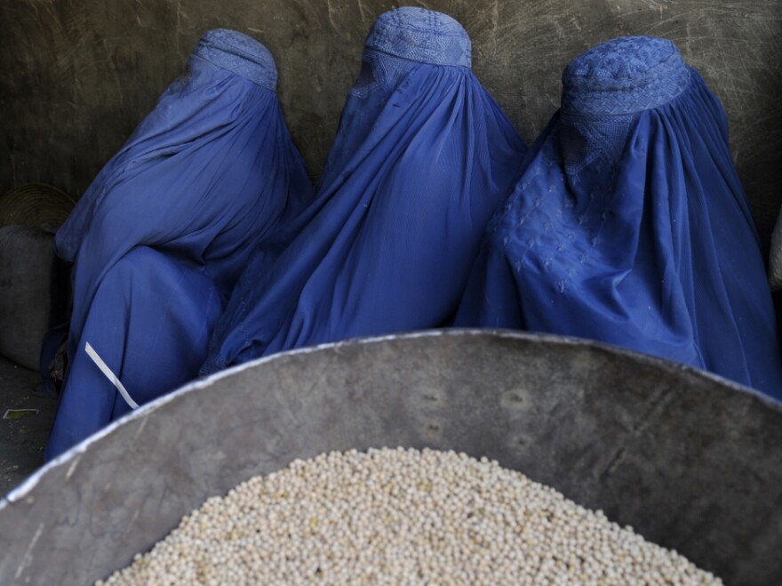 Burqa-clad Afghan women wait to buy chickpeas from a shop in Kabul earlier this year.
