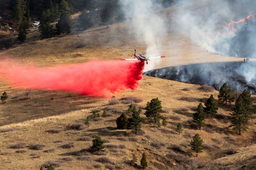 A single-engine plane drops fire retardant around the NCAR fire burning near Boulder's Table Mesa neighborhood. March 26, 2022. Incident Commander for Boulder Fire Rescue Mike Smith said lower wind speeds and an ability to use aircraft helped firefighters keep the blaze from reaching neighborhoods.