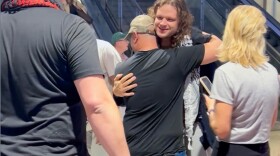 A man is hugged after exiting an escalator at Austin Bergstrom International Airport. 