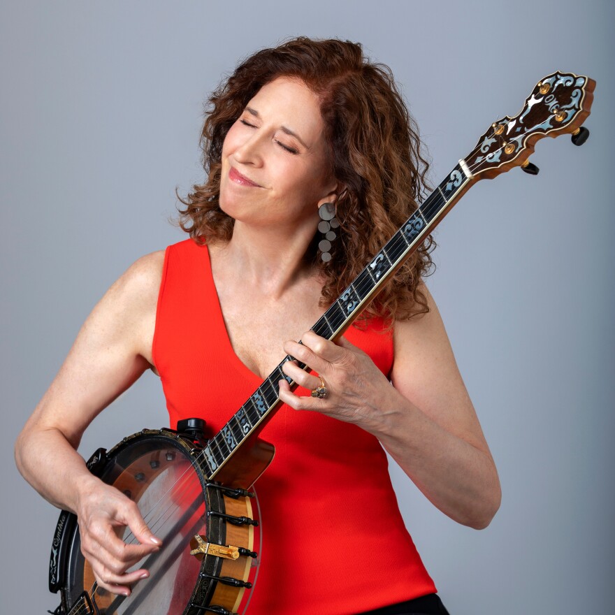 Woman wearing red dress strums banjo.