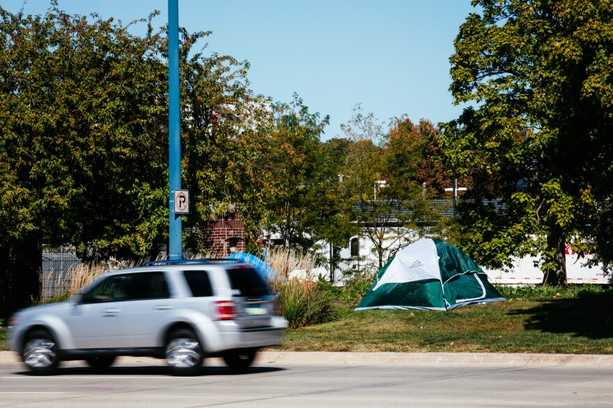 A small, silver SUV passes on the street near a