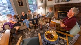 Pam McColl, Jacqui Comstock, her husband Holger Buchholz, Jacqui’s mother, Ruth Comstock, and Pam’s husband, Will McColl, have a conversation in the McColl’s living room in Roslindale. (Jesse Costa/WBUR)